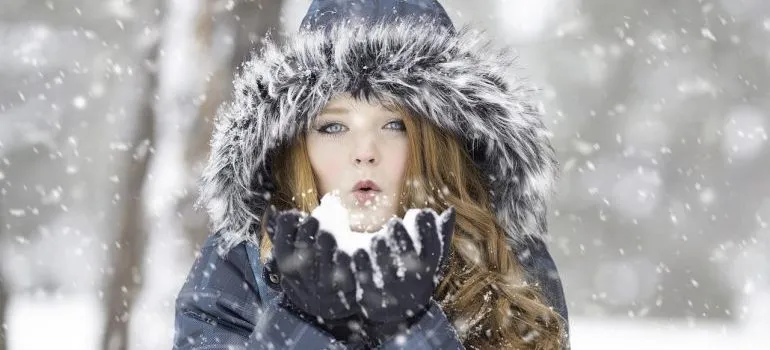 A girl blowing snow out of her hands.