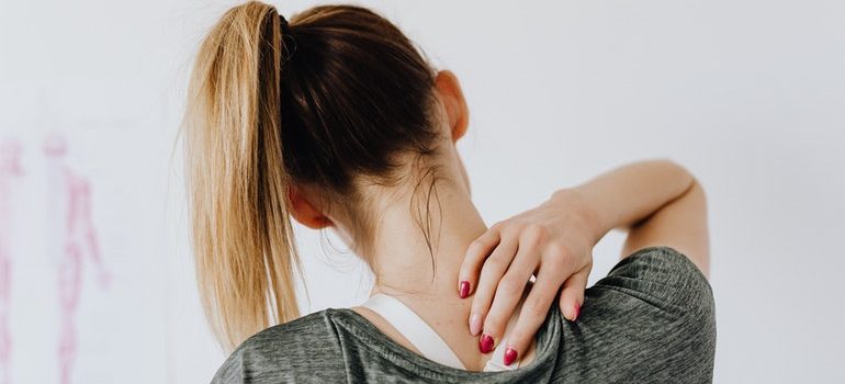 Person massaging their neck to avoid moving day injuries.