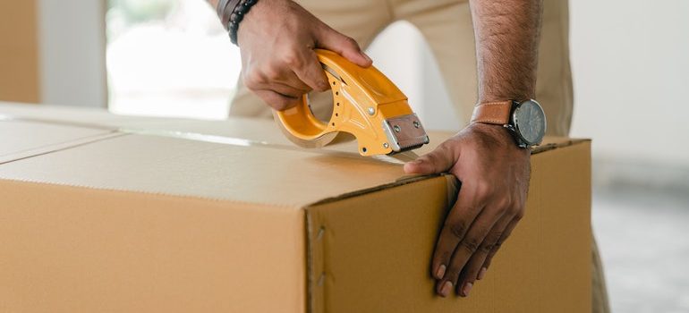 Person taping a box used to protect fragile items during transport.