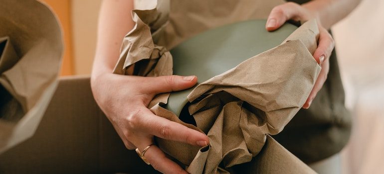 Person wrapping a dish in paper.