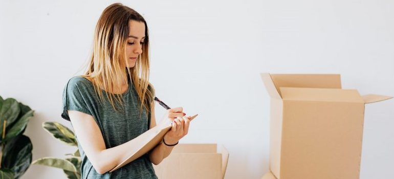 woman writing, moving boxes behind