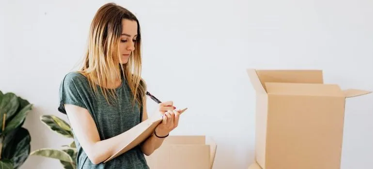woman writing, moving boxes behind