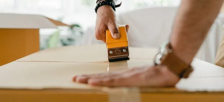 Man packing a box after hiring commercial equipment movers