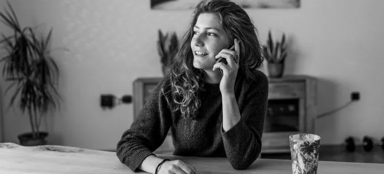 A woman on the phone, calling to book furniture installation services. 