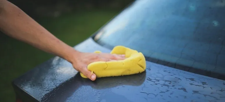 Person washing a car while preparing vehicles for transport.