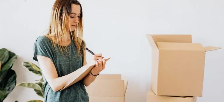 woman-writing-moving-boxes-behind