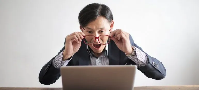 A person looking at a laptop screen with a surprised expression.