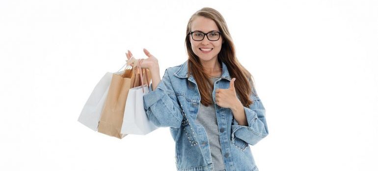A girl holding shopping bags and giving a thumbs up.