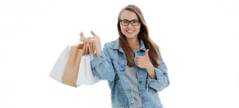 A girl holding shopping bags and giving a thumbs up.