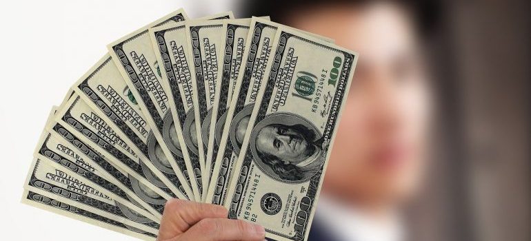 A person holding dollar bills to use for hiring 3PL companies.