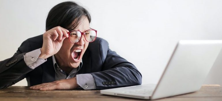 person with glasses looking at the laptop, yelling