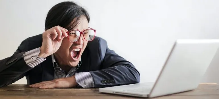person with glasses looking at the laptop, yelling