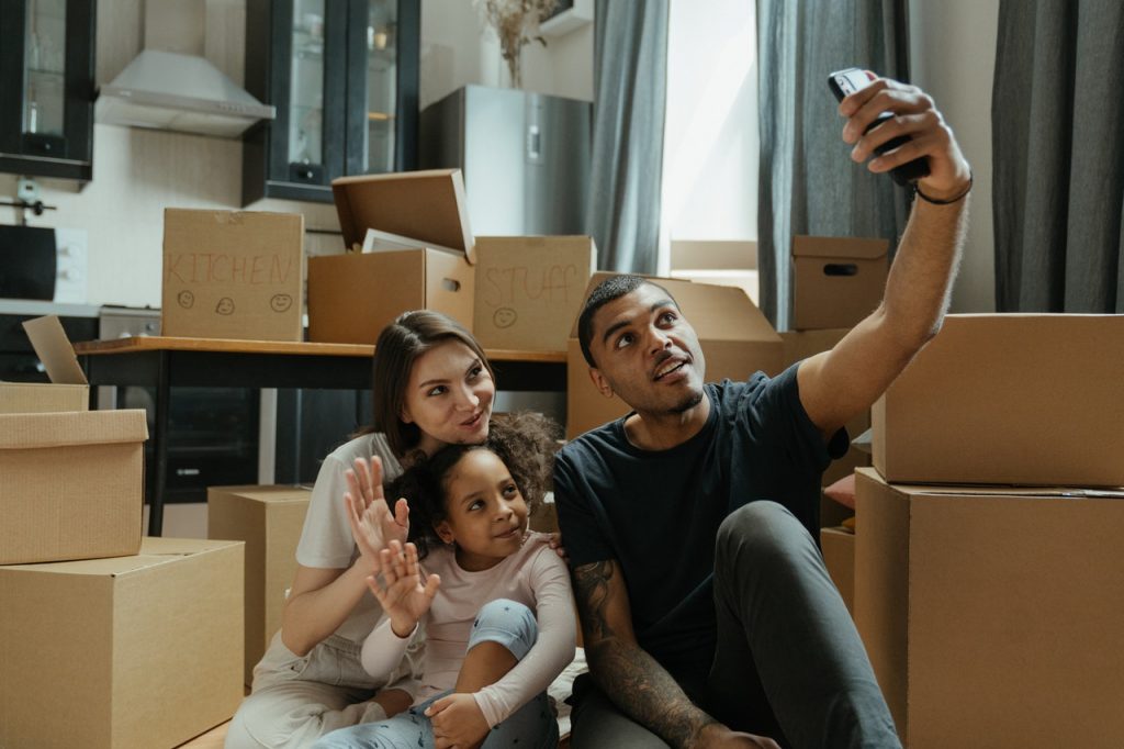 Family taking a photo while sitting surrounded by moving boxes