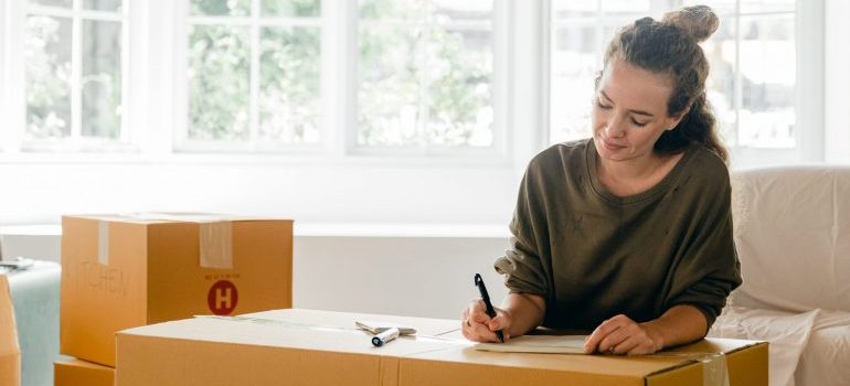 woman preparing for the move, writing a list on the cardboard box