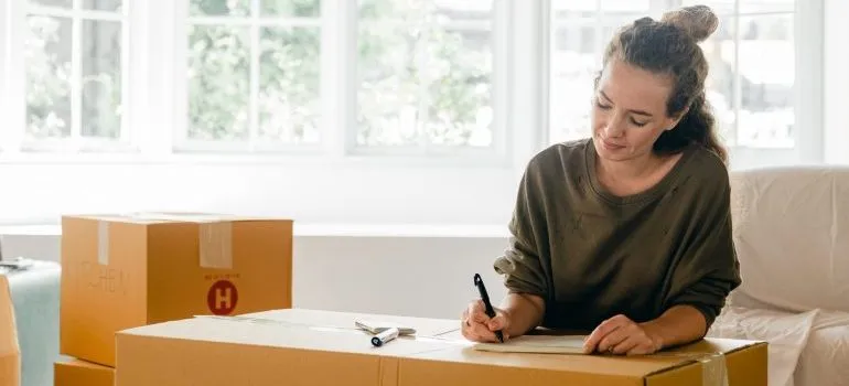 woman preparing for the move, writing a list on the cardboard box