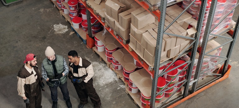 Three workers talking in a warehouse.