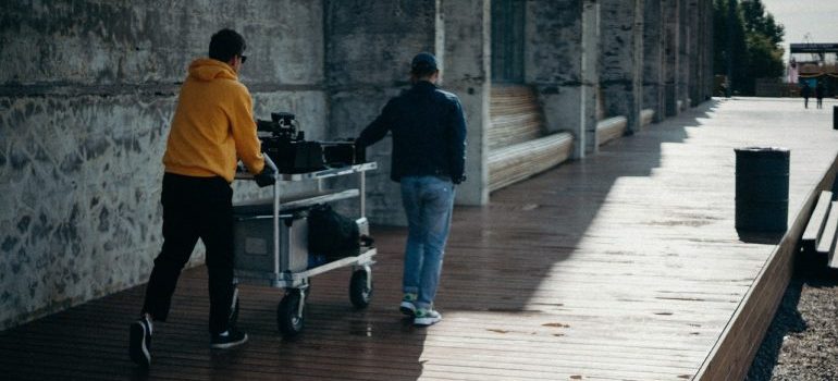 Two guys hauling equipment.