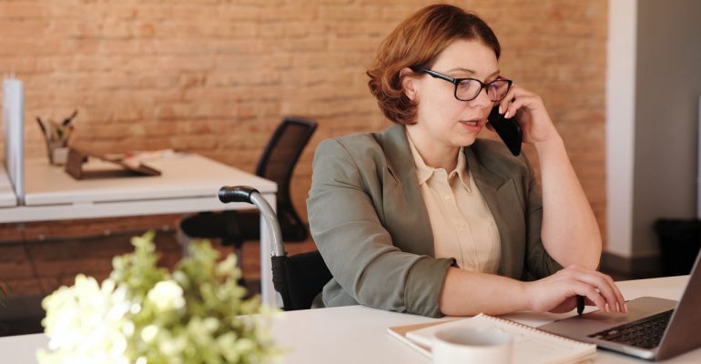 Woman making a call while looking at her laptop.