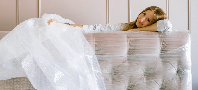 Woman leaning her head on a wrapped up sofa.