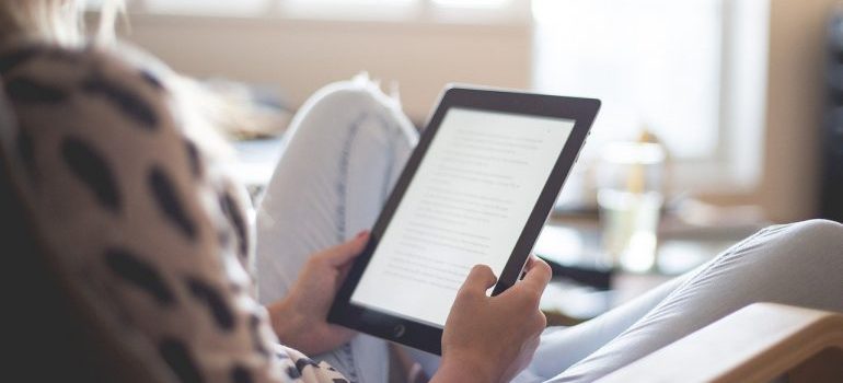 A woman holding a tablet, reading about things to know before renting self-storage.
