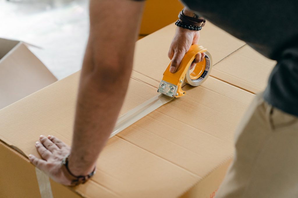 Man sealing box with packing tape