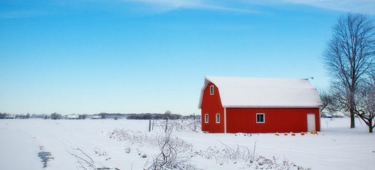 A red barn in the middle of a snowy field.