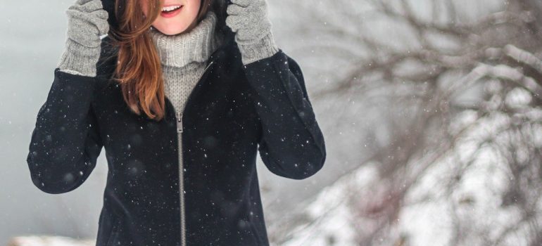 A woman in winter clothing with snowflakes around her.