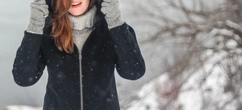 A woman in winter clothing with snowflakes around her.