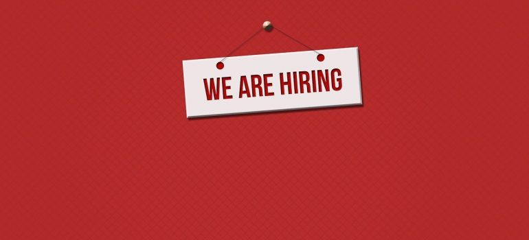 A we are hiring sign on a red surface.