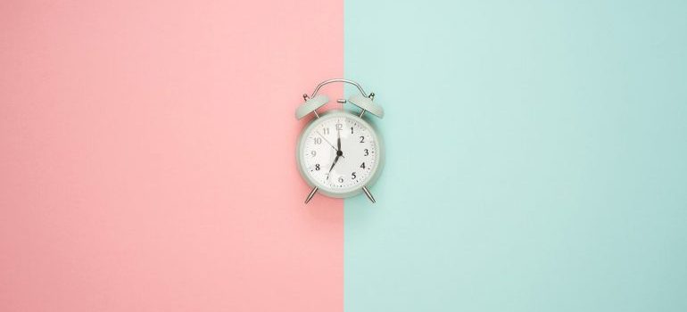 An alarm clock on a pink and blue surface.