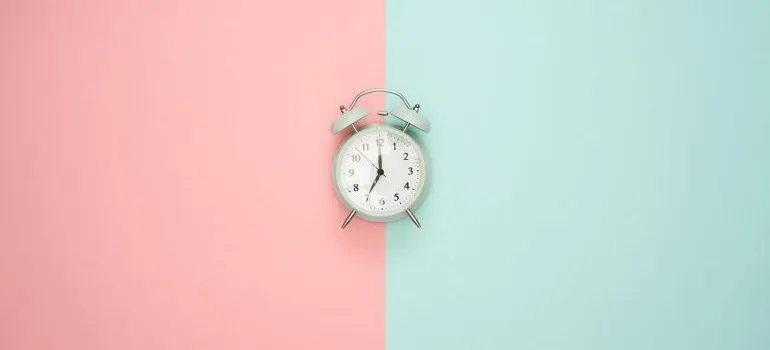 An alarm clock on a pink and blue surface.