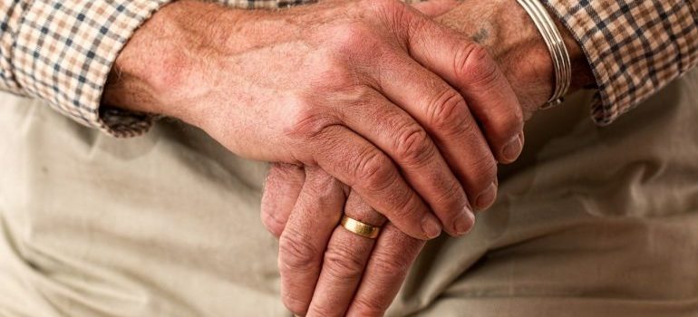 An elderly person with crossed hands.