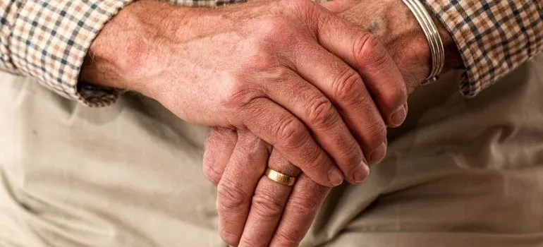 An elderly person with crossed hands. 