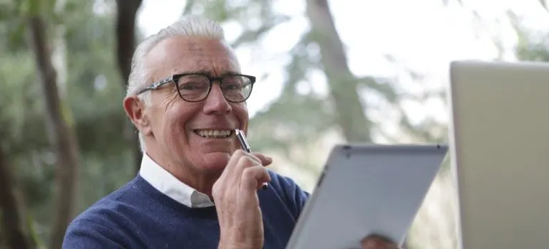 Smiling elderly man holding a pen and a tablet