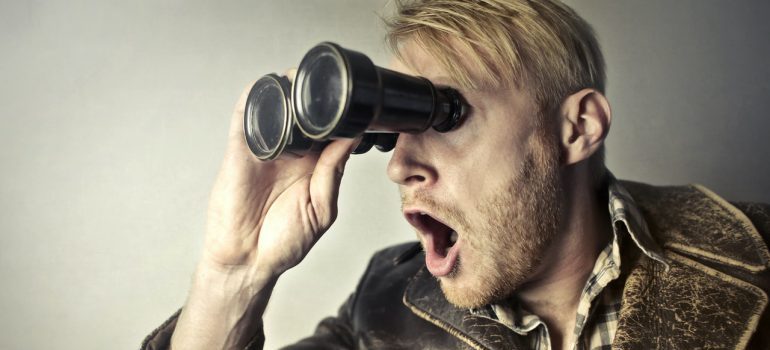 A surprised man using binoculars