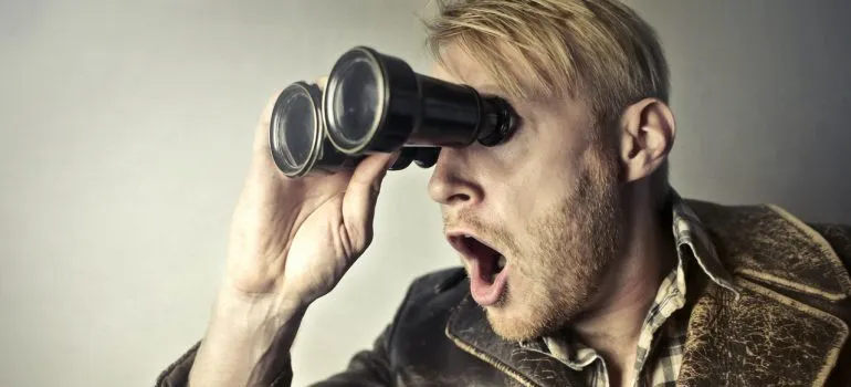 A surprised man using binoculars