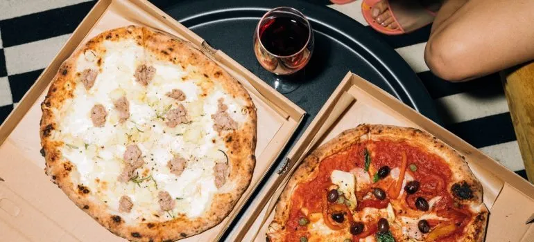 Two wine glasses next to two pizzas.