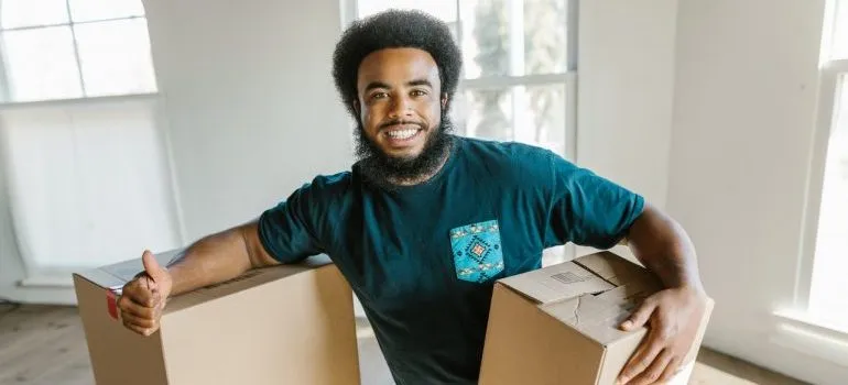 A mover holding a box and giving thumbs up for moving without disrupting your neighbors.