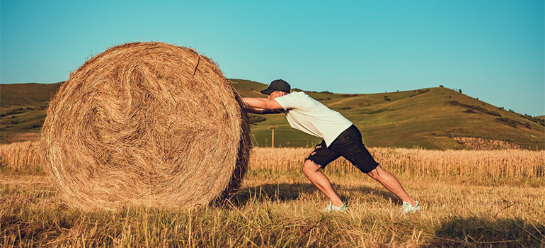 A man pushing a hay stack
