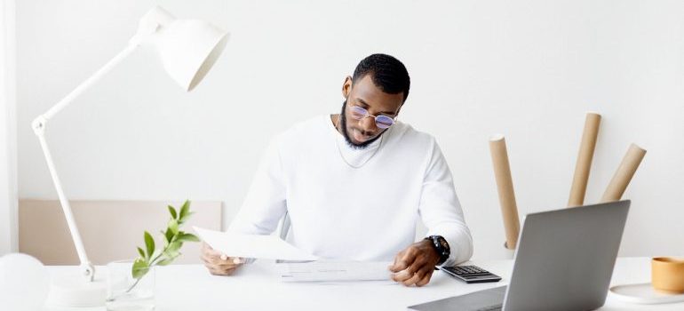 A man in white calculating expenses before buying a vacation home overseas