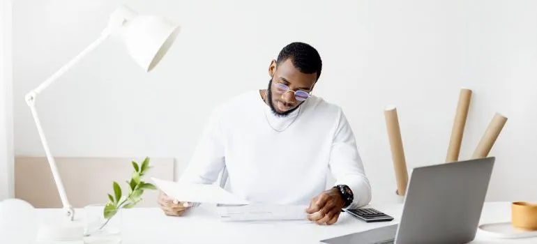 A man in white calculating expenses before buying a vacation home overseas