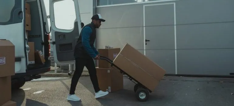 A person using dolly to move boxes.