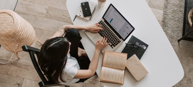 A top-down view of a woman using laptop to find out all about buying a vacation home overseas.