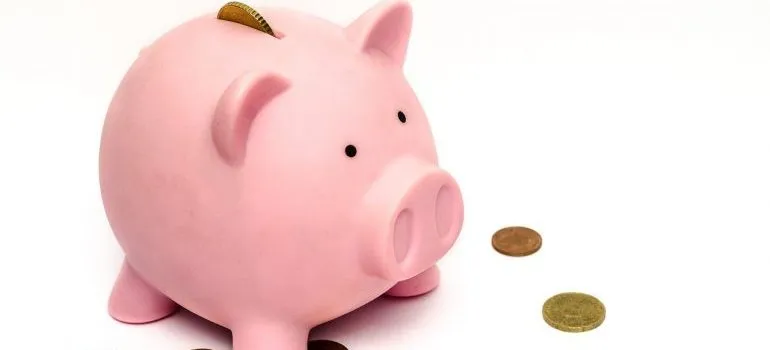 A piggy bank with some coins around it.