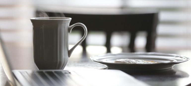 A cup of coffee and a plate on a table.