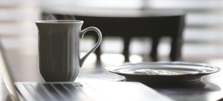 A cup of coffee and a plate on a table.