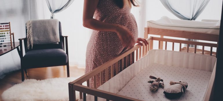 Pregnant woman standing next to a crib