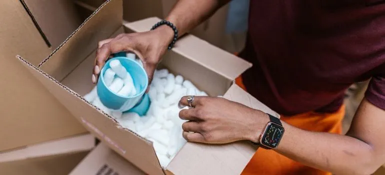 A person holding a blue cup of packing peanuts.