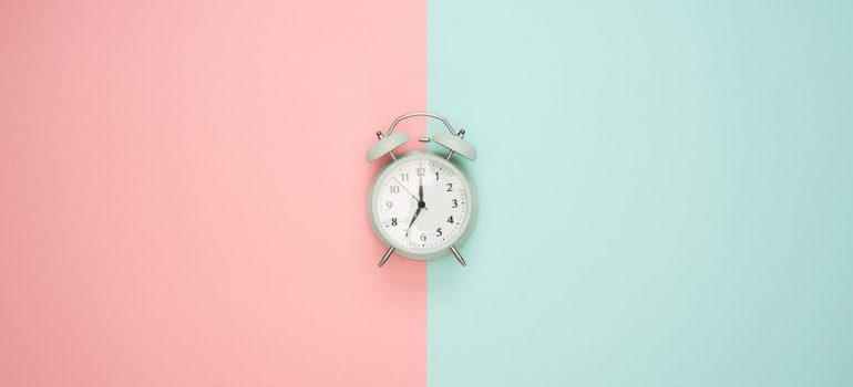 An alarm clock on a pink and blue surface.