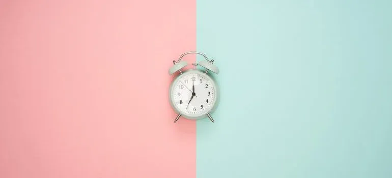 An alarm clock on a pink and blue surface.